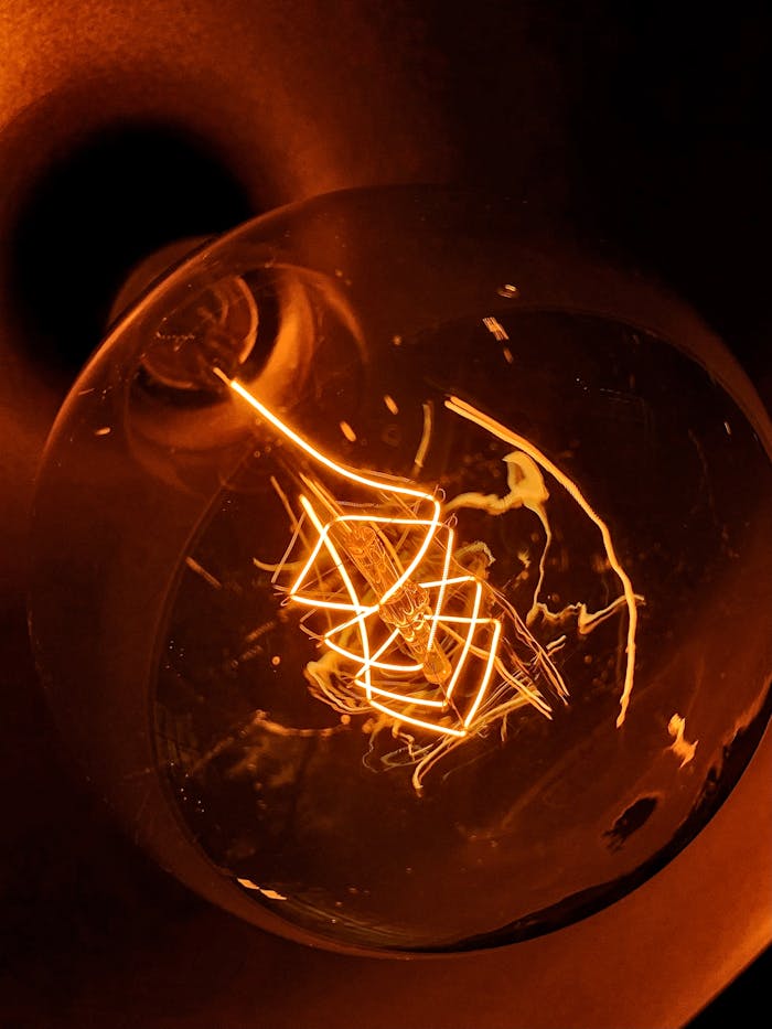 Detailed macro shot of an illuminated vintage incandescent light bulb filament.