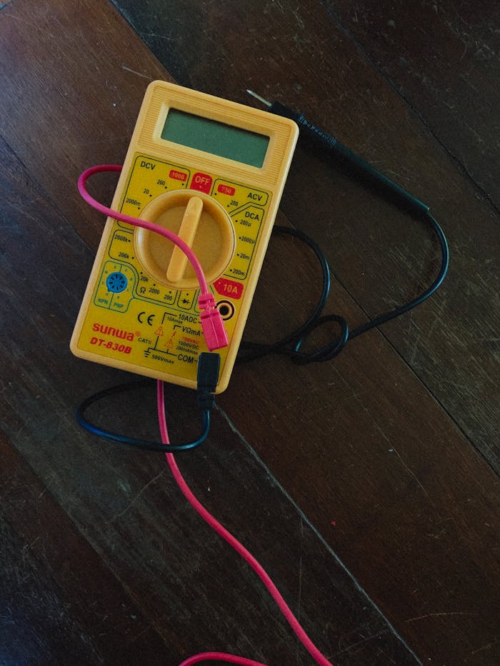 A digital multimeter with wires on a wooden surface, focused view.